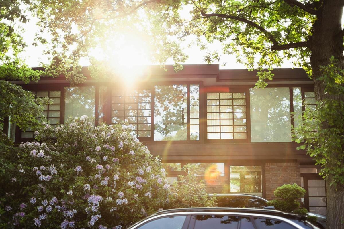 brick 2-story home with big trees and sun